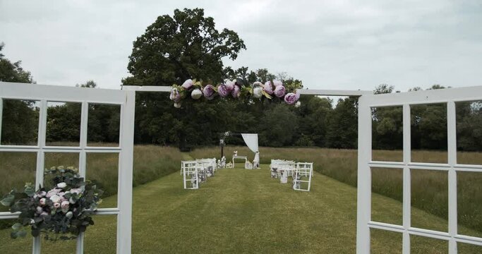 wide view through wedding arch between decorated chairs at wedding ceremony