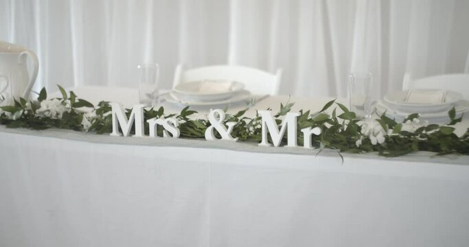 amazing view of Mr. and Mrs. inscription with wedding bouquet and some plates in background.