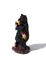 Detail shot of a designer figurine of a black bear standing on its hind legs. There are many gnomes in bright clothes on the bear. The original handmade statuette is isolated on the white background.