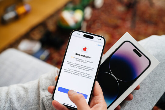 London, United Kingdom - Sep 28, 2022: POV Woman Hand Holding The Package Showing Newly Released IPhone 14 Pro By Apple Computers - Looking At The Apple Care Plus  Warranty Plan With Unlimited Repairs