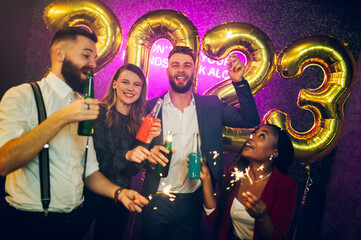 Multiracial people with sparklers and drinks celebrating new years eve in the club