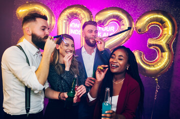 Multiracial people with party trumpets and drinks celebrating new years eve