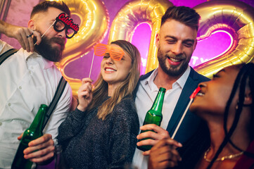 Multiracial friends celebrating new years eve with party props and drinks in the club