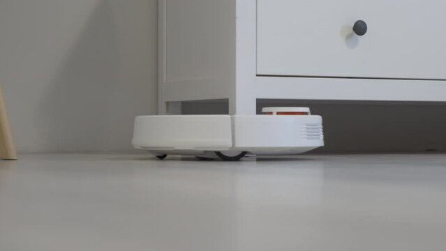 Modern White Robotic vacuum cleaner working house floor