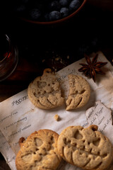 Cookies in the shape of pumpkins and ghosts are in a plate on the table. Next to a teapot and mugs, an autumn still life
