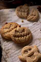 Cookies in the shape of pumpkins and ghosts are in a plate on the table. Next to a teapot and mugs, an autumn still life