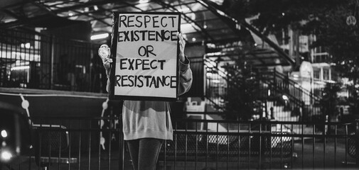 Grayscale of a protest sign with editable text being held by a young female protester
