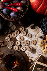Runes lie on a wooden table next to cookies in the form of pumpkins and ghosts