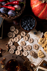 Runes lie on a wooden table next to cookies in the form of pumpkins and ghosts