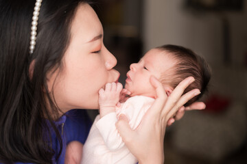 lifestyle shot on young and happy Asian Chinese woman holding tenderly her adorable newborn baby girl in her arms in mother and daughter love and care concept