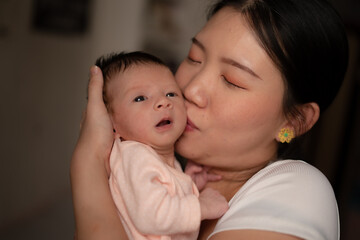 lifestyle shot on young and happy Asian Chinese woman holding tenderly her adorable newborn baby girl in her arms in mother and daughter love and care concept