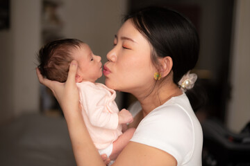 lifestyle shot on young and happy Asian Chinese woman holding tenderly her adorable newborn baby girl in her arms in mother and daughter love and care concept