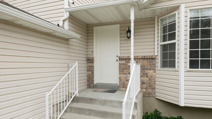 Panorama Entrance of a house with white vinyl wood siding and bay windows