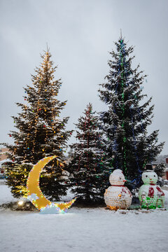 Two big snowman made of plastic bottles, standing under a Christmas tree in the city square. Christmas eco theme. New Years decor