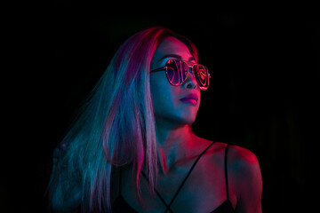 Closeup portrait of asian young pretty woman with naked shoulders in red neon light on dark...