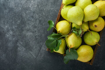 Pears. Fresh sweet organic pears with leaves in wooden box or basket on old dark gray stone...