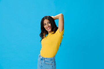 Woman in yellow t-shirt on blue background posing gestures emotions and signals with smile, hands up happiness copy space