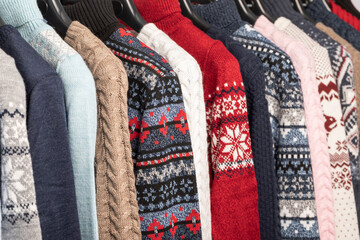 Various vintage sweaters on clothing rack in second hand store