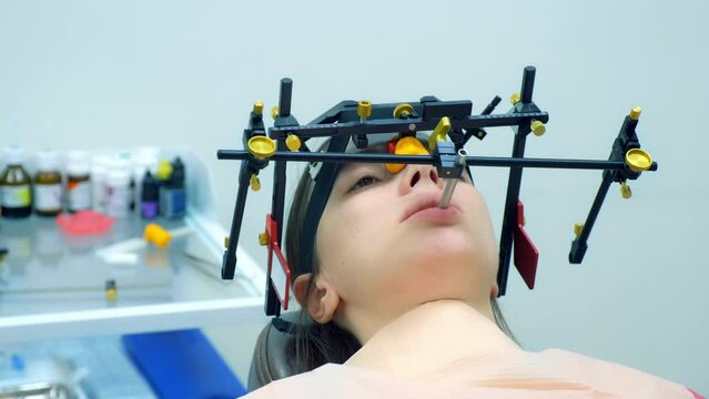 Orthodontist is doing condylography procedure to woman patient. Examination and treatment of mandibular joints. Orthodontology treatment and cure concept. Dentistry and clinic.