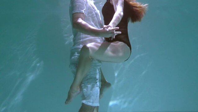 A woman and a guy are swimming underwater. A woman kisses a guy underwater.