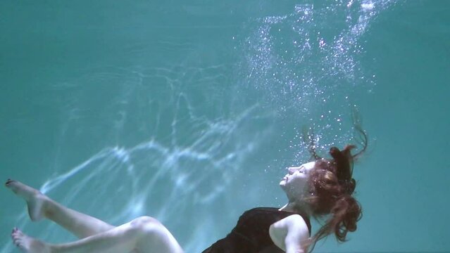 A pregnant girl swims and dives under the water. Medical training for a pregnant woman with a big belly will dive underwater. Woman learning to give birth in water.