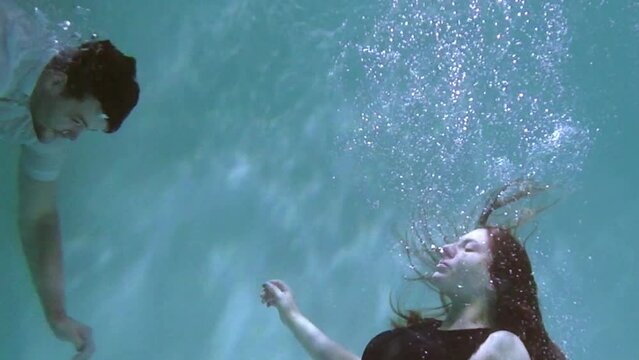 A pregnant girl swims and dives under the water. Medical training for a pregnant woman with a big belly will dive underwater. Woman learning to give birth in water.
