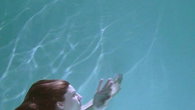 A pregnant girl swims and dives under the water. Medical training for a pregnant woman with a big belly will dive underwater. Woman learning to give birth in water.