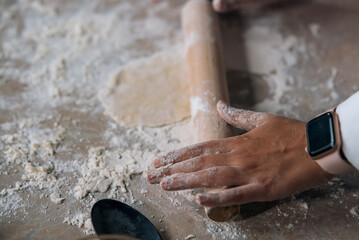Close-up of young woman rolling dough with rolling pin