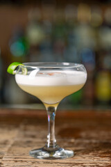Vanilla Sour cocktail with egg white and lemon juice  on the bar. Blurred background.