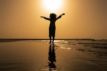 Young woman in summer dress and hat during sunset at sea