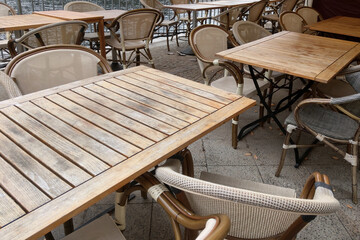 Empty wooden chairs and tables on the terrace of a cafe or restaurant.