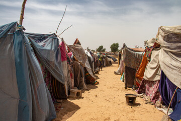 Refugee camp in Africa, full of people who took refuge due to insecurity and armed conflict. People living in very poor conditions, lack of food, clean water and proper shelter to stay in - obrazy, fototapety, plakaty