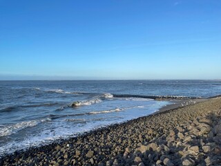 Der Westteil der Nordseeinsel Baltrum ist mit aufgeschütteten Felsen und Buhnen befestigt. Die Wellen branden dort am Abend im Herbst. 