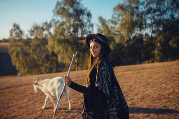 A female shepherd grazes goats on a meadow - 541706739