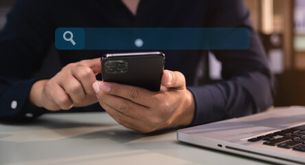 Male are using a mobile phone search information on the desk in the morning.