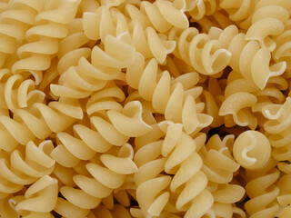 Raw spiral pasta background. Background of pasta closeup. Raw food background or texture close up. Spiral uncooked macaroni wallpaper