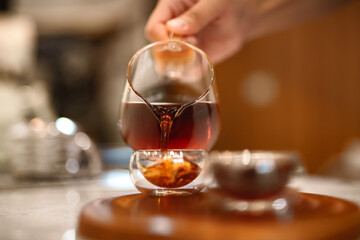 Barista making a Geisha coffee, pouring hot water from kettle over a ground coffee powder