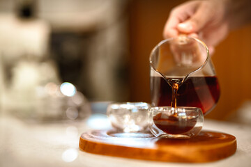 Barista making a Geisha coffee, pouring hot water from kettle over a ground coffee powder