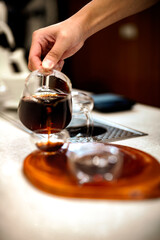 Barista making a Geisha coffee, pouring hot water from kettle over a ground coffee powder