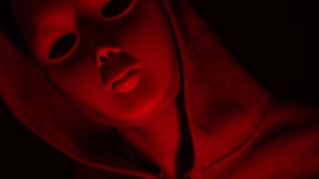 Man wearing a mask and wearing a hoodie in red tones, Halloween concept.