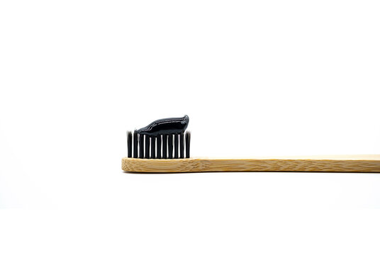 Whitening black charcoal toothpaste on bamboo toothbrush, close up. Eco natural product for dental hygiene.