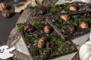 Halloween concept food. Flatbread or pizza with squid Ink, green cheese, mushrooms and purple onion