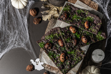Halloween concept food. Flatbread or pizza with squid Ink, green cheese, mushrooms and purple onion