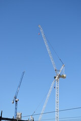 Modern buildings under construction with large cranes and machinery. 