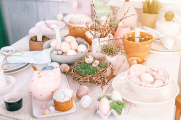 happy easter and spring holidays time. festive tablescape set decor. traditional dinner food easter eggs and baked cakes on table at home. rabbit and willow. pale pop pastel blue and pink color. flare