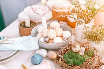 happy easter and spring holidays time. festive tablescape set decor. traditional dinner food easter eggs and baked cakes on table at home. rabbit and willow. pale pop pastel blue and pink color. flare