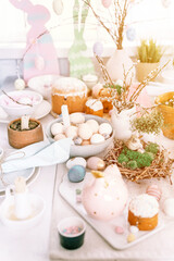 Fototapeta na wymiar happy easter and spring holidays time. festive tablescape set decor. traditional dinner food easter eggs and baked cakes on table at home. rabbit and willow. pale pop pastel blue and pink color. flare