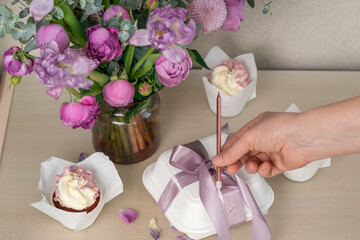 Cake packaging. The girl ties the ribbon to the packing box.