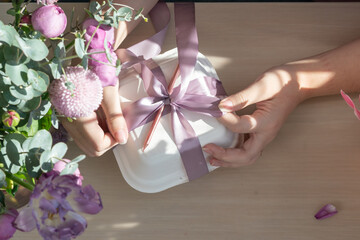 Cake packaging. The girl ties the ribbon to the packing box.