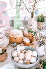 happy easter and spring holidays time. festive tablescape set decor. traditional dinner food easter eggs and baked cakes on table at home. rabbit and willow. pale pop pastel blue and pink color